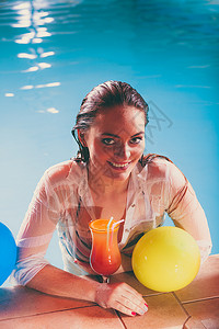 快乐的女子在游泳池边的缘放松图片