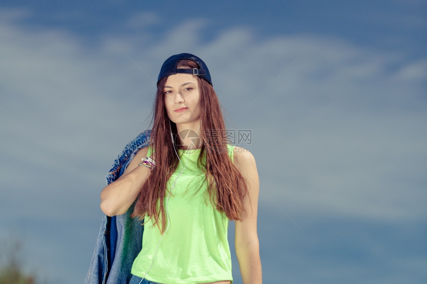 女青年在户外听音乐女青年在户外用耳机听音乐女青年在天空的肖像图片