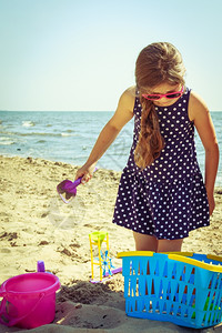 玩具的小女孩在沙滩上玩耍铲子在沙滩上挖洞的小孩暑假放松图片