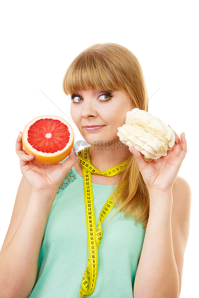 配有测量胶带的妇女握在手上蛋糕和葡萄精的选择中在甜食或新鲜水果之间作出决定饮食选择图片