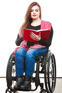 在轮椅上学习和阅读概念残疾和在轮椅上的年轻残疾妇女阅读书籍背景图片