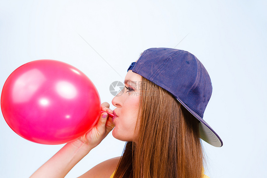 年轻女孩吹红气球青少年和派对准备庆祝特伦迪十几岁女孩吹红气球年轻美女为派对准备配件图片
