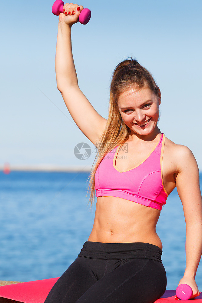 女在户外与哑铃一起运动女在户外与哑铃一起运动在海边场穿服的适合健身女孩图片
