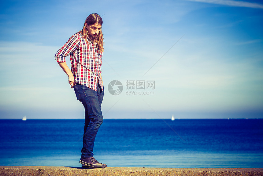 男子在海边的石墙上走来放松男子在夏日阳光明媚的下在石墙上走来去在海边来去放松图片
