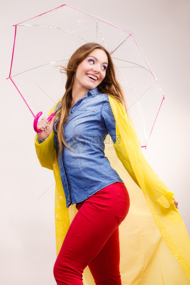 身着防水的黄色大衣站在雨伞下玩得开心图片