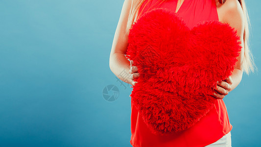 心形枕头放在手里情人节的爱红色心形枕头放在人手中的蓝色工作室里图片