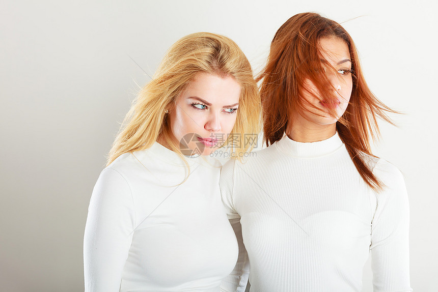 两个年轻朋友在一起女孩有白色的顶部站在对方旁边一个女人有金发第二个黑图片