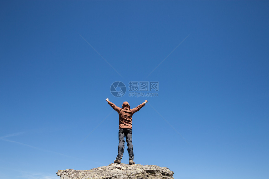 人站在山顶蓝色的天空上图片