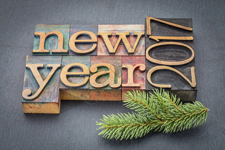 新年2017贺卡以旧纸质木板块形式在石背景和树枝上打印的文字图片
