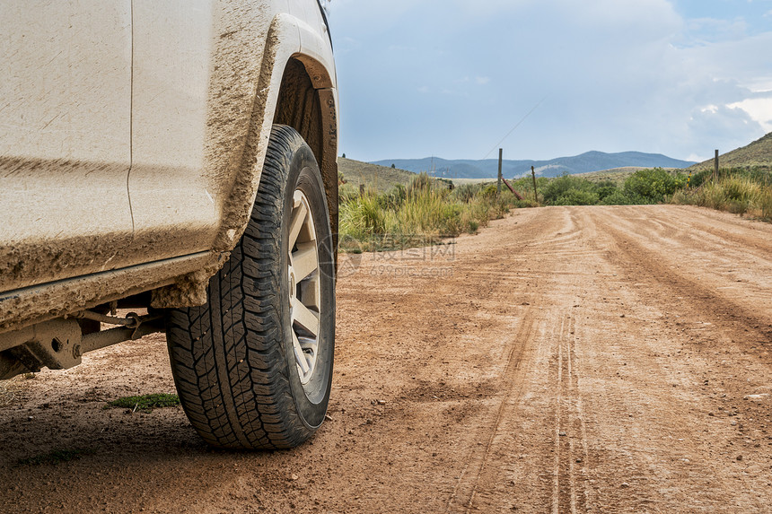 关闭四轮驱动SUV汽车驾驶在一条灰尘土路上图片
