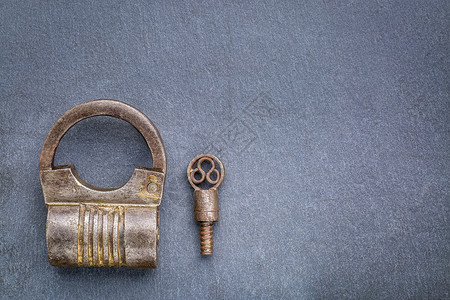 古老的圆形手工制作的螺丝旋铁型板锁钥匙在灰石上复制空间图片