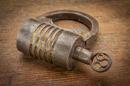 U型锁古老的圆形手工艺的螺丝式型铁链锁用钥匙在生锈的木柴上背景