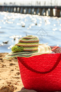 夏日沙滩上的威克篮子手提袋和帽威克篮手提袋包和沙滩子上的帽暑假图片