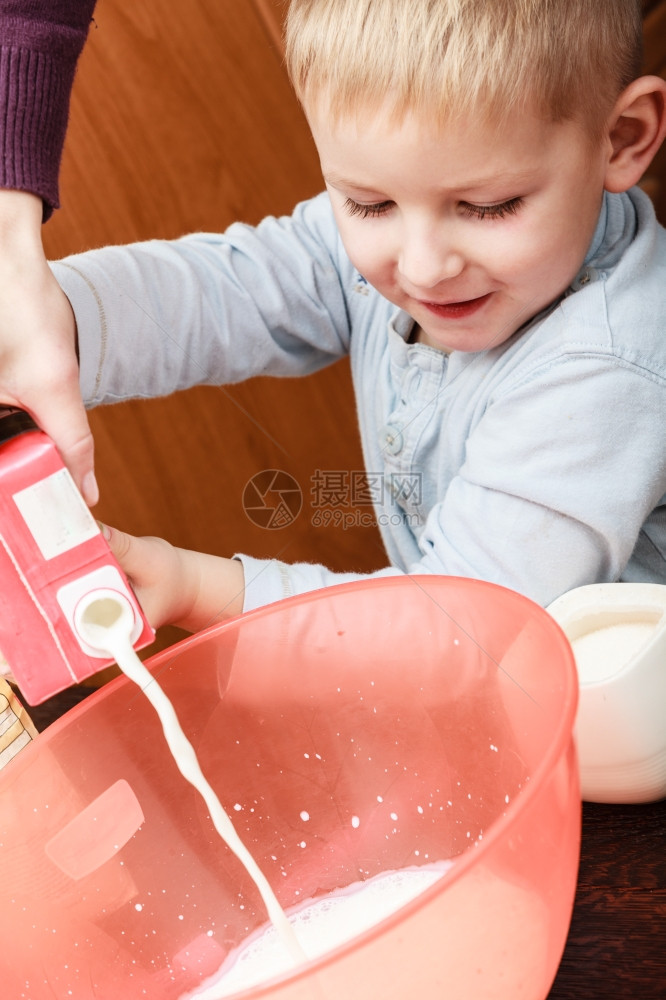男孩帮助父母在厨房做饭碗里准备倒牛奶图片
