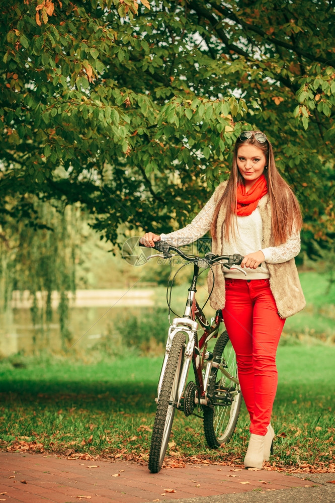 年轻女子在户外的森林公园推着自行车图片