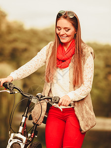 年轻女子在户外的森林公园推着自行车图片