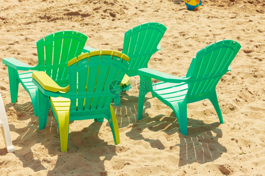 沙子上的绿色塑料椅夏天休息放松沙子上的四张绿色塑料椅阳光明媚的海滩上轻松地方图片