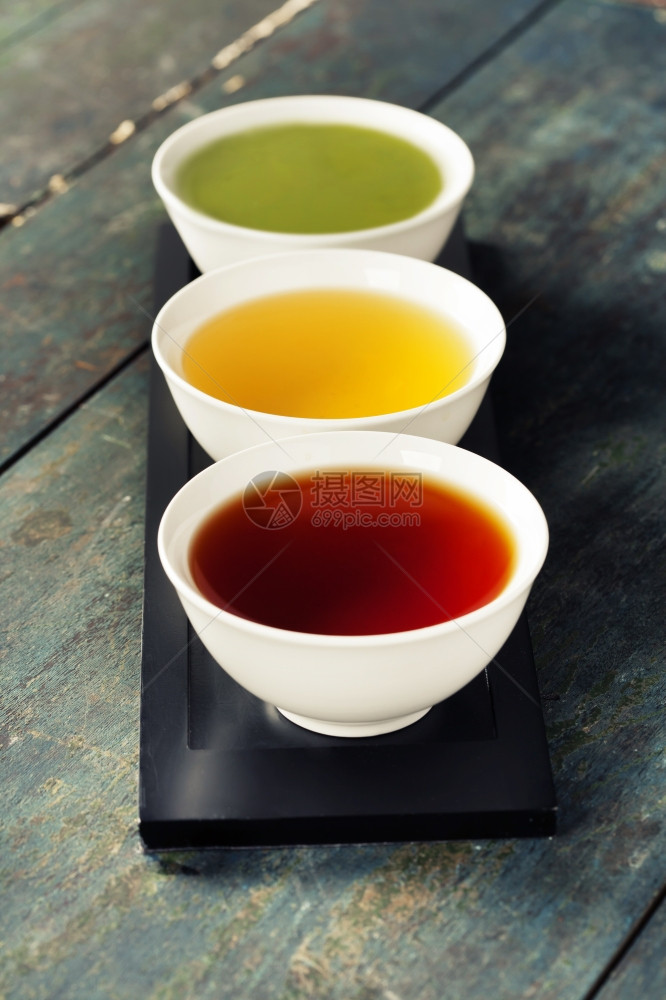 茶叶概念木制陶瓷碗本底不同种类的茶叶黑绿色和红图片