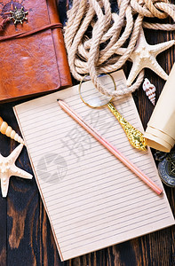 木制桌子笔记本和贝壳上的旅行物品图片