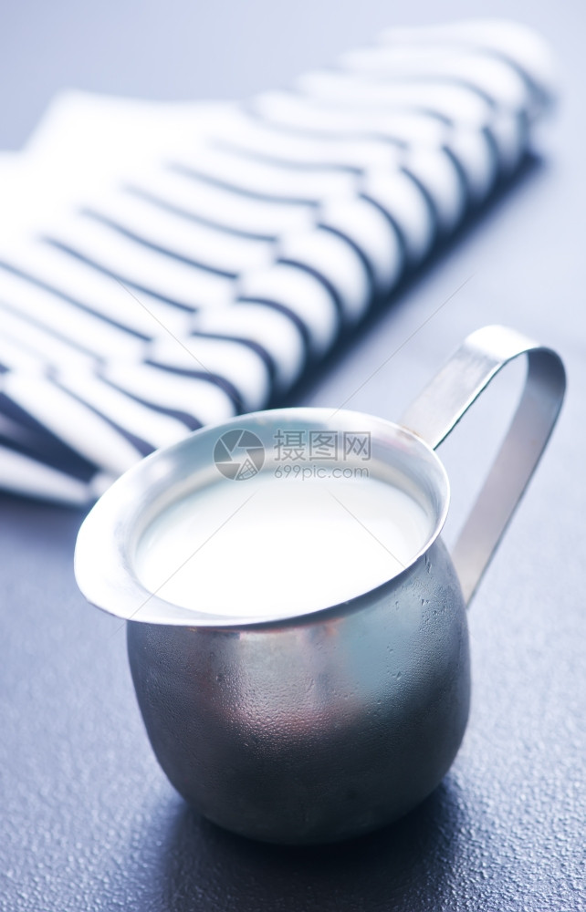 在金属罐中和一张桌子上装有鲜奶的金属罐中和在一张桌子上图片