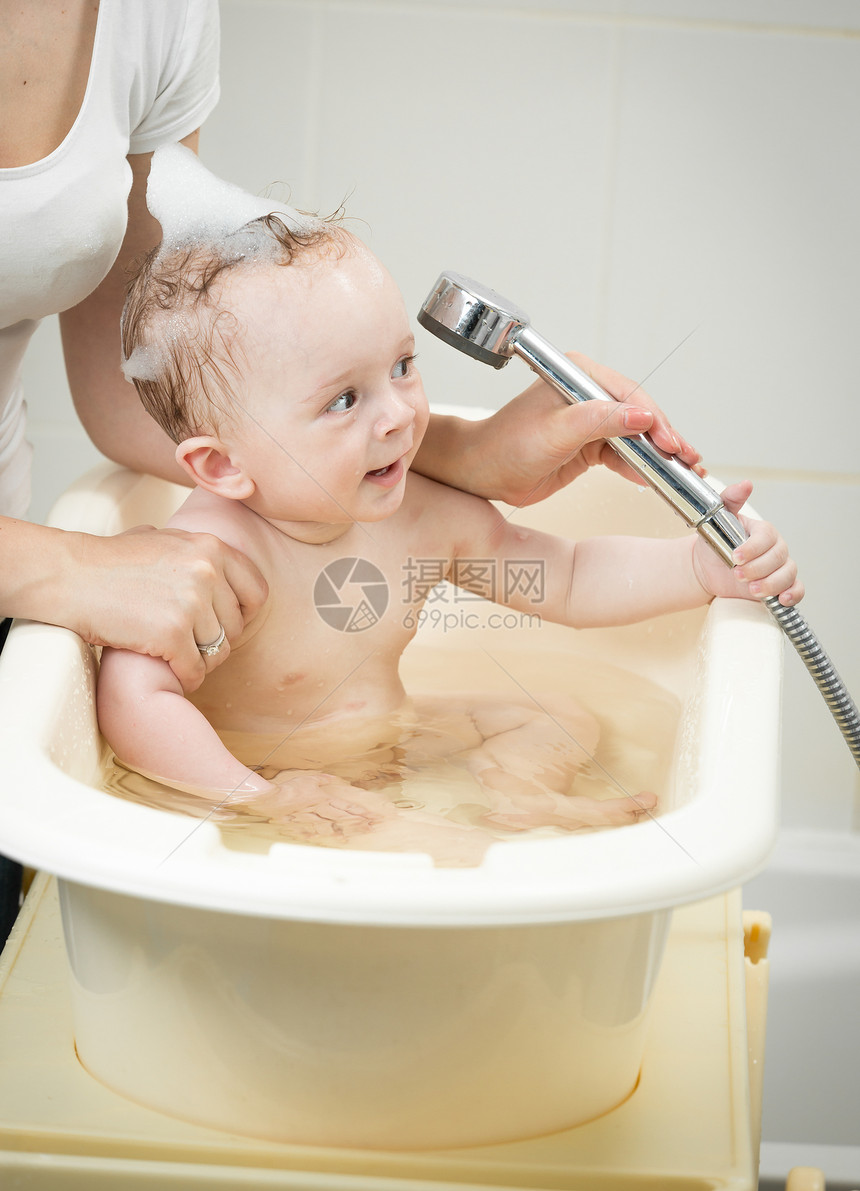 快乐的男孩在洗澡时与头一起玩图片