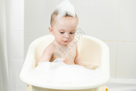 洗澡的男孩在洗澡时玩泡沫的可爱小男孩肖像背景