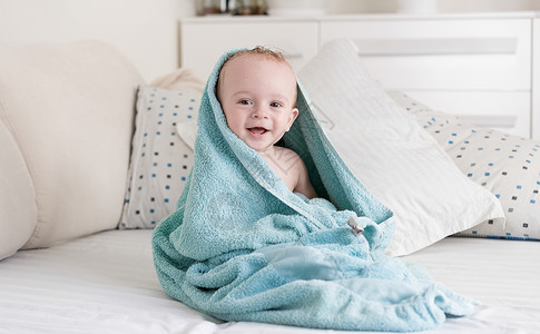 洗完澡后带着蓝毛巾的婴儿笑着快乐背景图片
