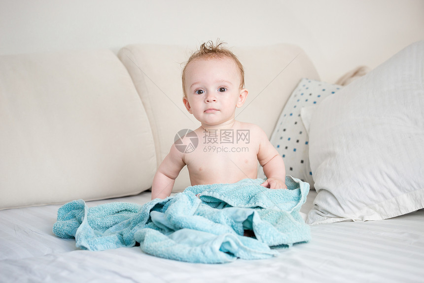 洗澡后坐在床上的9个月大男孩快乐图片