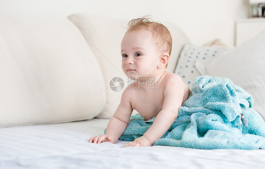 在客厅沙发上用蓝色毯子洗完澡后可爱的男孩图片