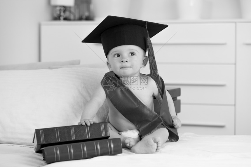 毕业时可爱小男孩的黑白画像坐在沙发上的书图片