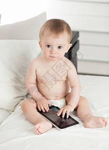 用数字平板电脑在床上拍摄可爱小男孩的画像图片