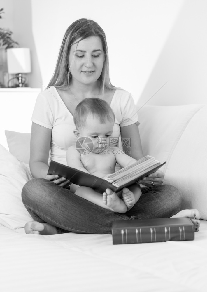 带着微笑的年轻母亲读书给孩子看的黑白画像图片
