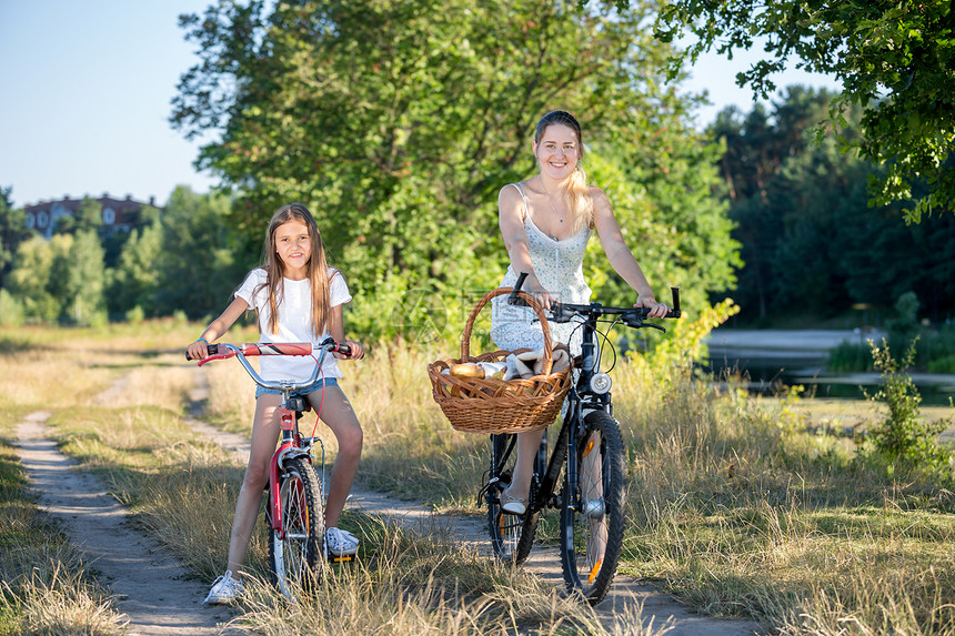 年轻母亲骑自行车与女儿一起野餐图片