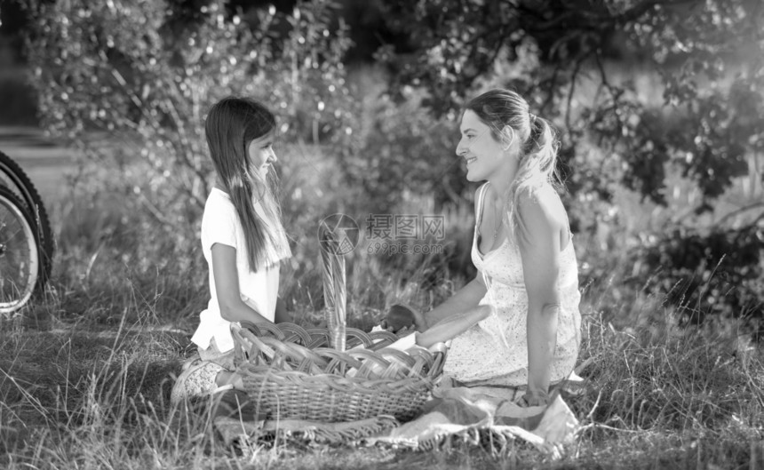 快乐的年轻女子与儿在野餐中放松的黑人和白肖像图片