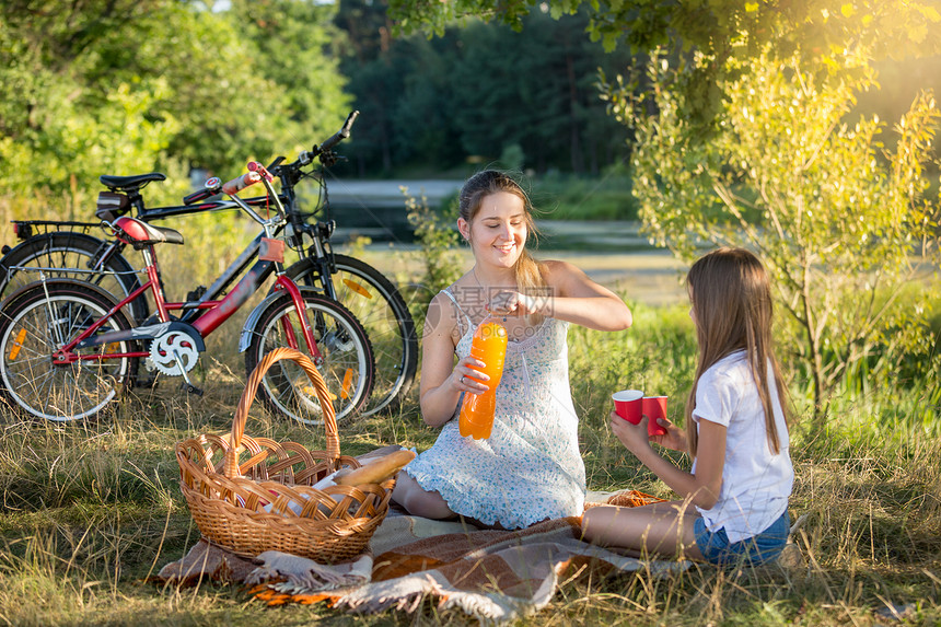 与10岁女儿一起在河边野餐的快乐少女背景是两辆自行车图片