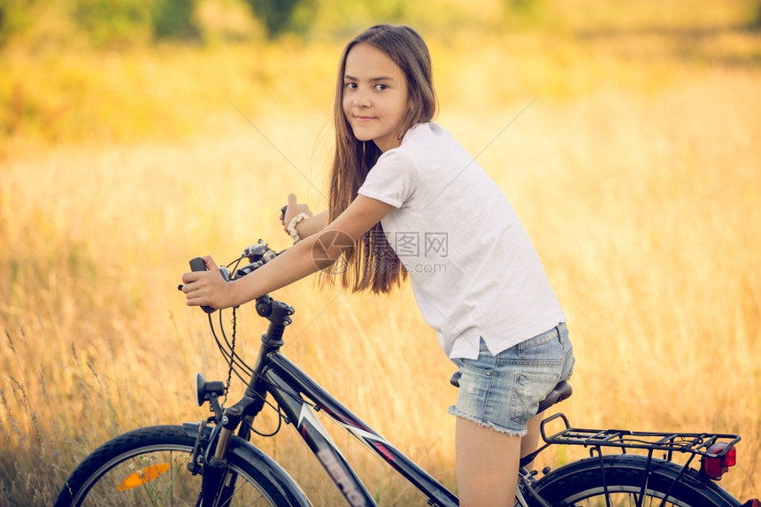 美丽的少女在草地上骑自行车图片