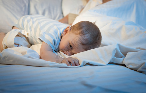 蓝色睡衣晚上睡在大枕头的可爱小男孩背景