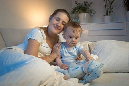 年轻母亲夜间与女婴躺在床上的触摸画像图片