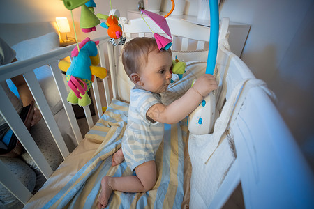可爱小男孩的肖像站在婴儿床和玩具旋转木马图片