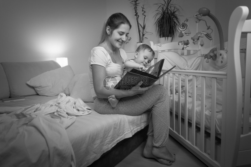 年轻母亲在睡觉前给儿子看书的黑白画面图片
