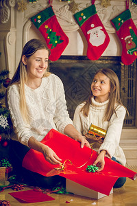 快乐的年轻母亲和快乐的女儿装饰圣诞礼物的画像图片