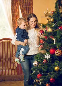10个月大的儿子和装饰圣诞树的母亲图片