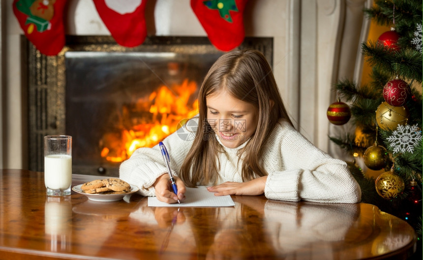 可爱女孩的肖像在圣诞节前夕写信给圣诞老人图片