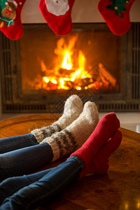 在燃烧的壁炉里暖羊绒袜子中男女双脚的近视图像图片