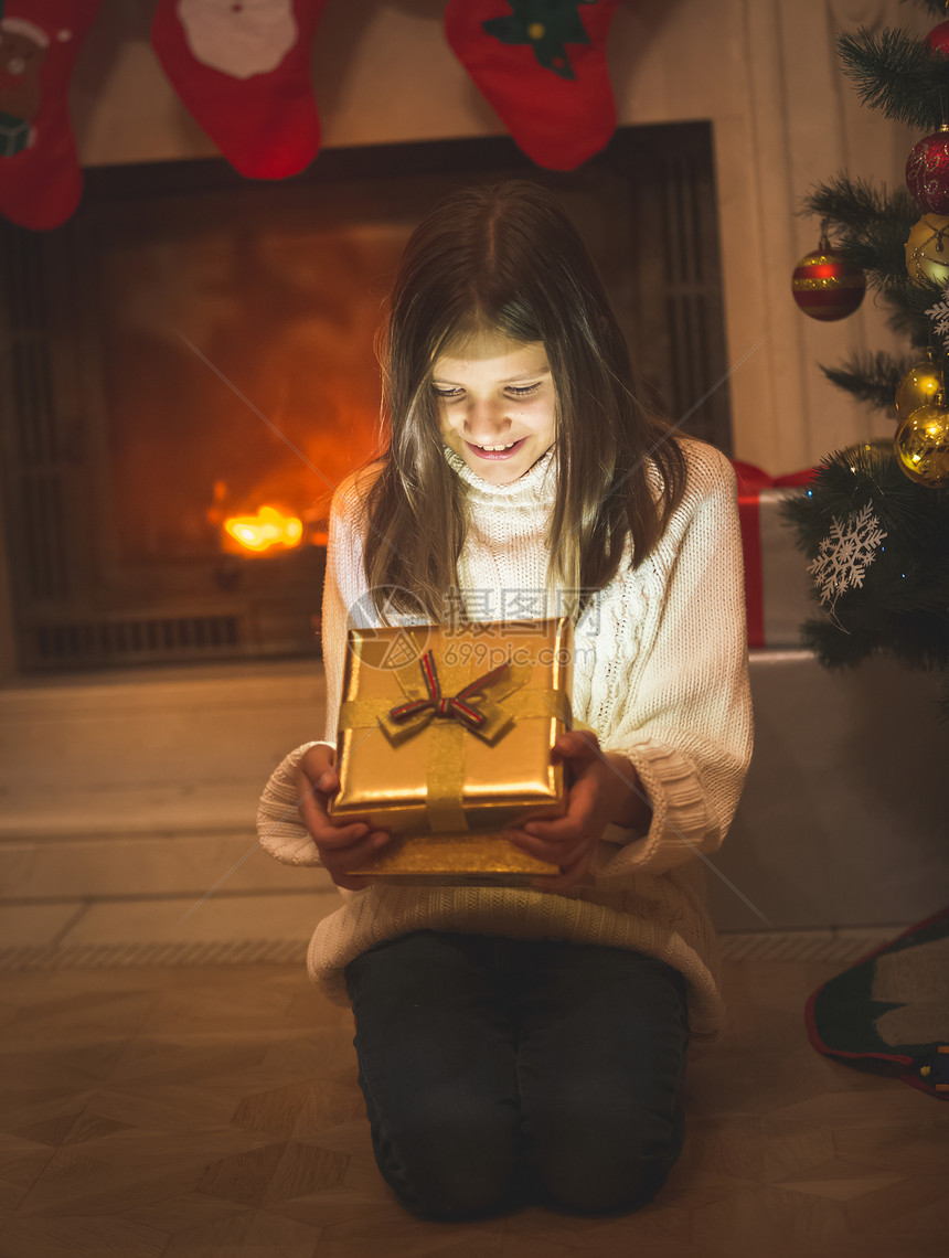 坐在壁炉的地板上打开圣诞礼物盒图片