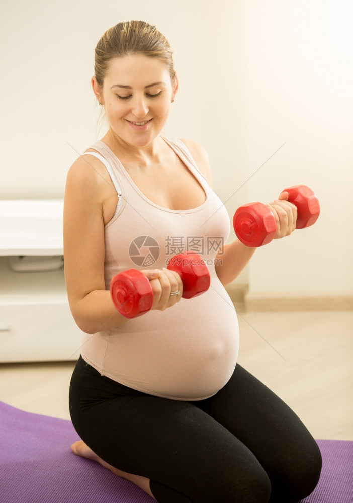 孕妇坐在垫子上并举着哑铃的触摸画像图片