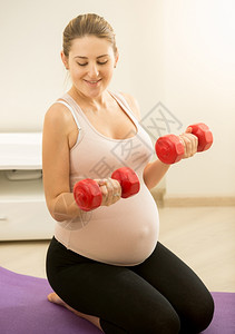孕妇画像孕妇坐在垫子上并举着哑铃的触摸画像背景