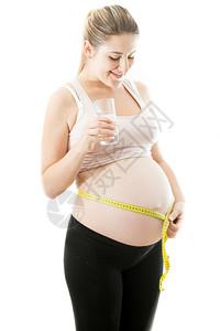 快乐的孕妇用测量胶带腹部的肚子肖像图片