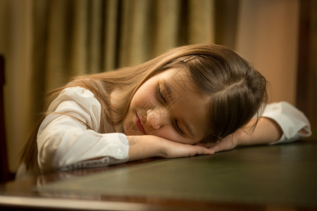 可爱的疲累女学生在书桌上睡觉的特写肖像背景图片