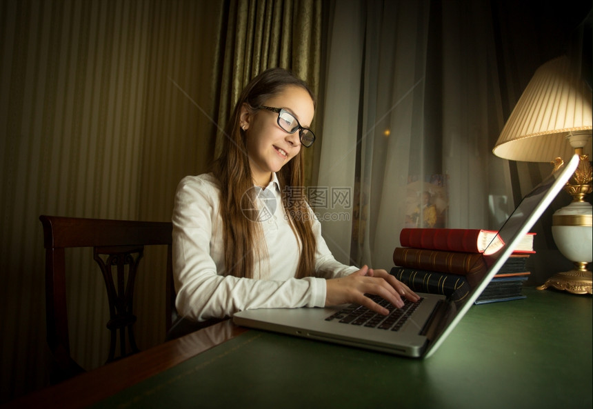 穿着白衬衫的可爱女学生在暗房笔记本上做家庭作业的肖像图片